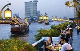 “Bangkok riverside view with temple and boats at sunset”
