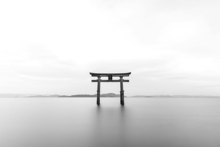 Japan Serene black and white image of a torii gate standing in calm waters, symbolizing tranquility.